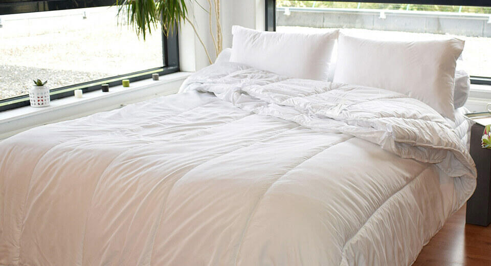 couette et oreillers blanc sur un lit